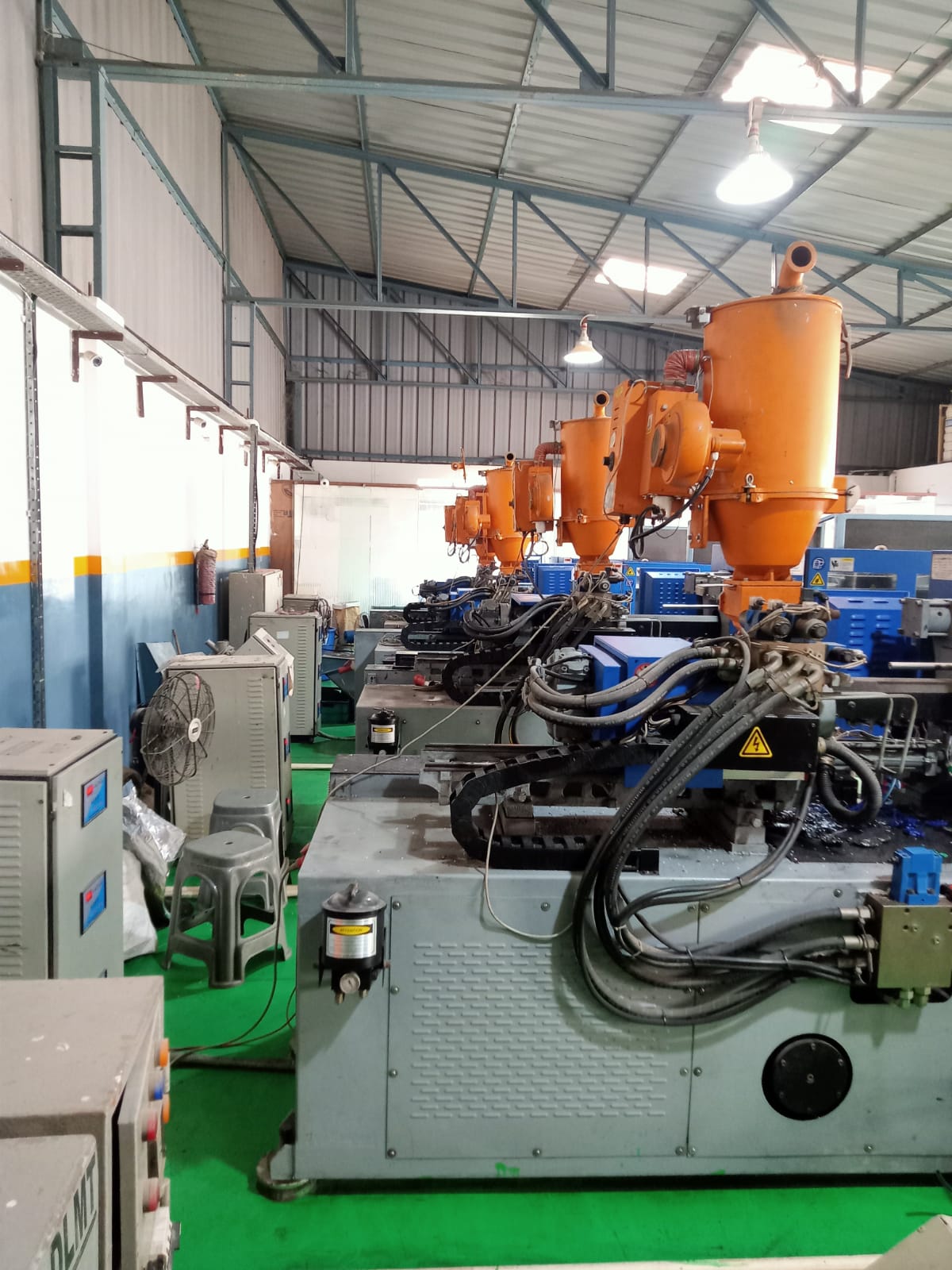 Row of injection molding machines with material hoppers at NEXA PLASTICS
